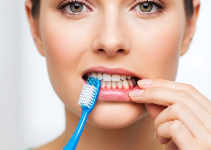 Close-up of a woman brushing her teeth with a blue toothbrush and white toothpaste, focusing on oral hygiene and dental care.